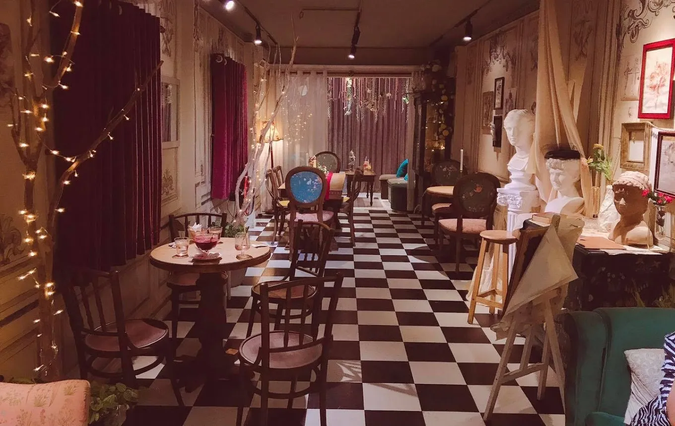 Góc trang trí lộng lẫy với ghế bành, tủ gương vintage và tông màu pastel tại quán cà phê phong cách Pháp hiện đại