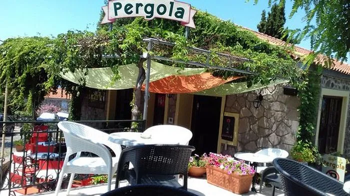 Hình ảnh một góc quán Pergola Cafe với kiến trúc cổ điển, màu trắng và dàn cây xanh bao phủ