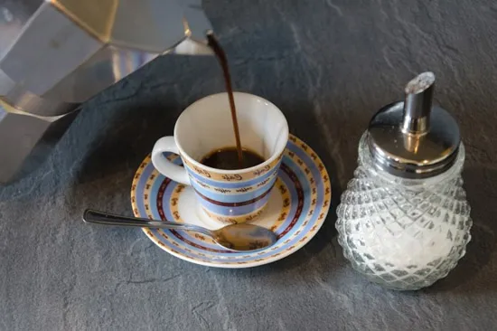 Ly cà phê Moka thơm ngon đã hoàn thành được rót trực tiếp từ bình Moka Pot ra tách sứ trắng.