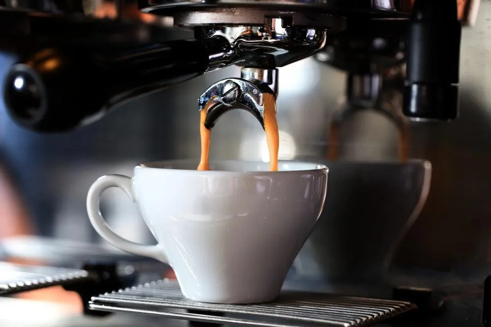 Máy pha cà phê chuyên nghiệp đang chiết xuất shot espresso vàng óng