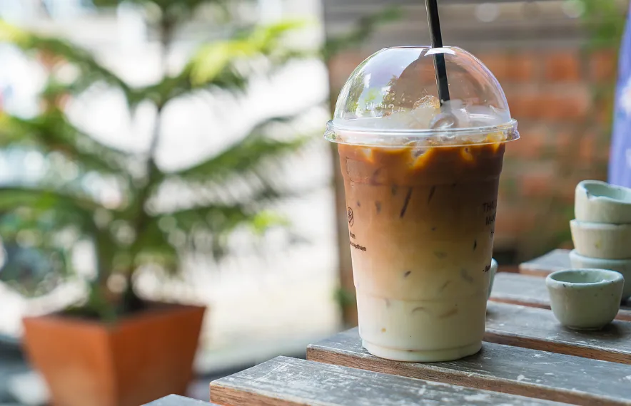 Một cốc cà phê latte với lớp bọt sữa hình nghệ thuật đặt trên quầy bar gỗ