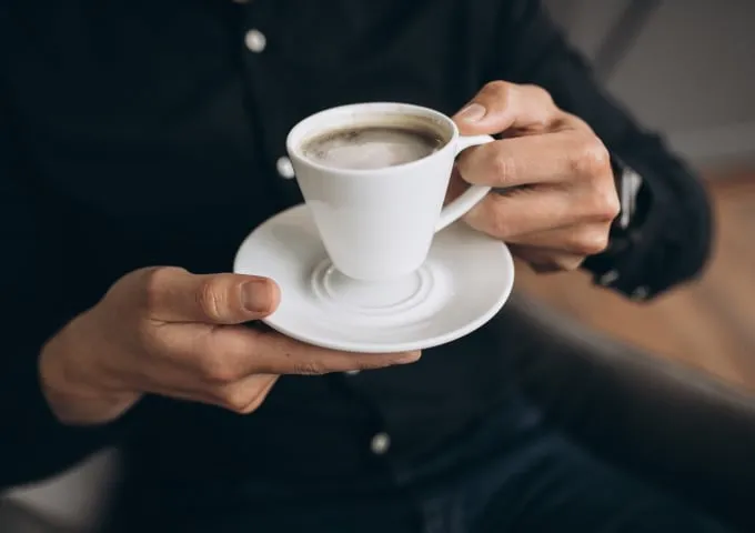Một ly cà phê ấm áp đặt cạnh các loại thảo mộc giúp giảm đau bụng kinh, cân bằng dinh dưỡng
