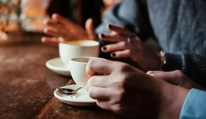 Một ly cà phê Americano đá mát lạnh, đặt cạnh máy pha cà phê và các dụng cụ pha chế chuyên nghiệp, minh họa các biến thể của Americano