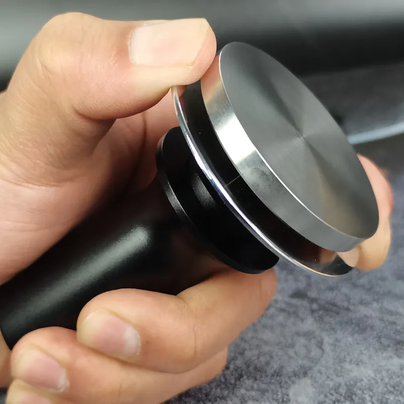 Một tamper nén lò xo chất liệu thép không gỉ đang được đặt trên phin lọc