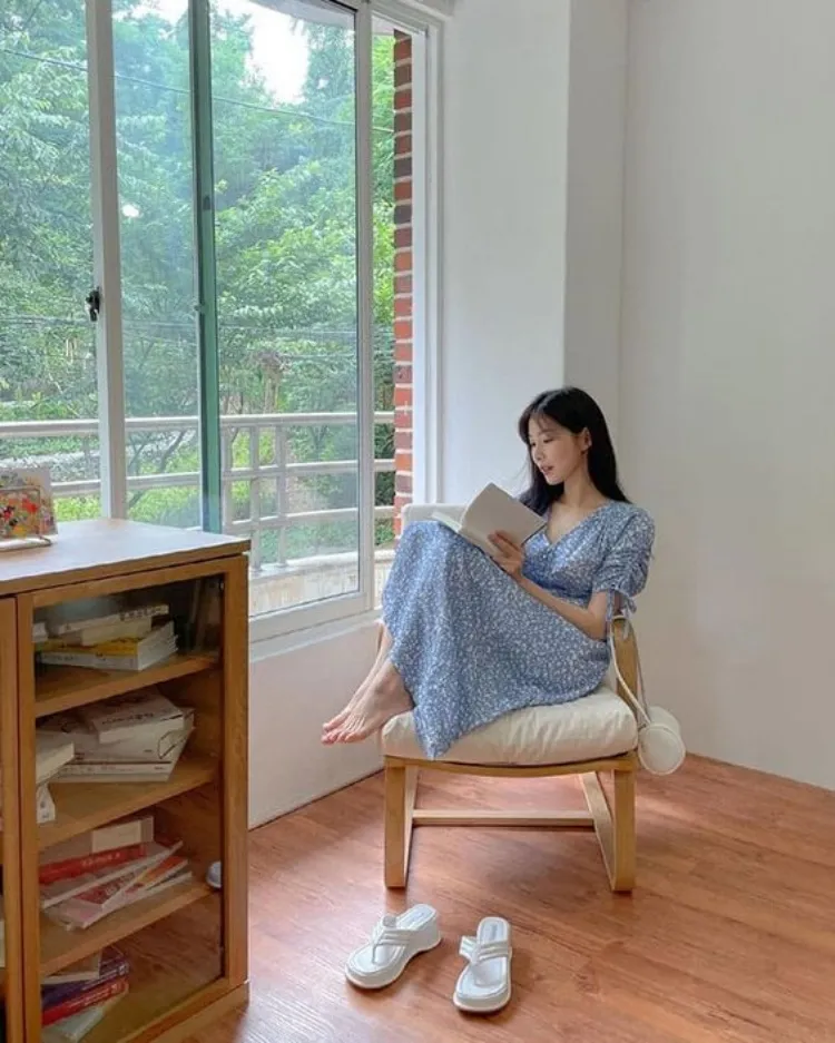 Người mẫu tạo dáng thoải mái bên cửa sổ, tận dụng ánh sáng dịu nhẹ để làm nổi bật vẻ đẹp tự nhiên