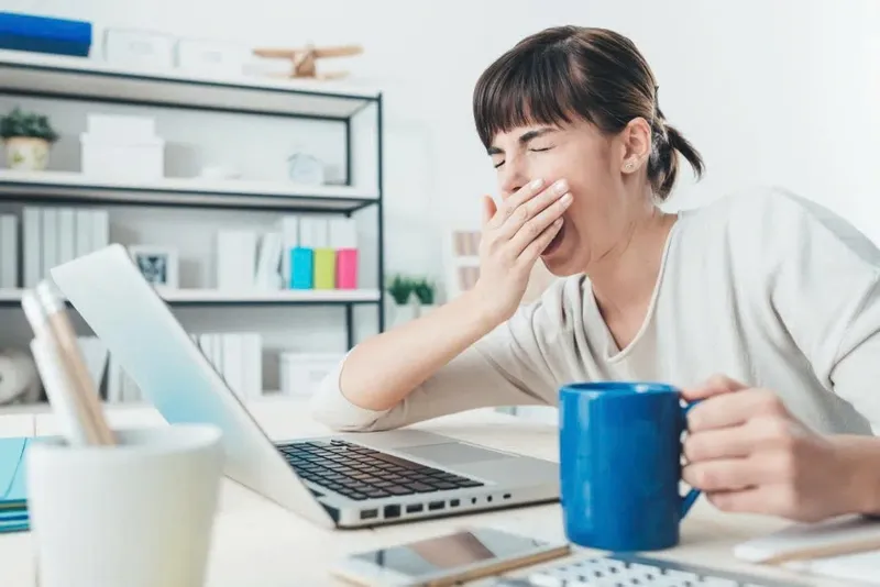 Người phụ nữ đang làm việc với tách cà phê trên bàn, thể hiện sự tập trung