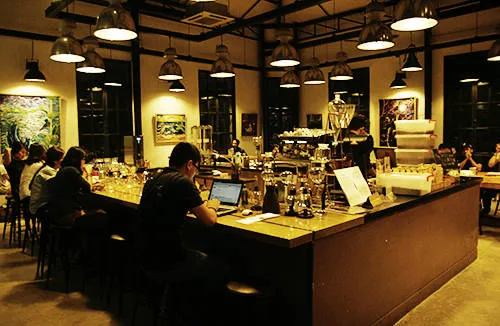 Quán The Workshop trên đường Ngô Đức Kế với thiết kế không gian ánh sáng vàng ấm cúng, bàn gỗ dài sang trọng