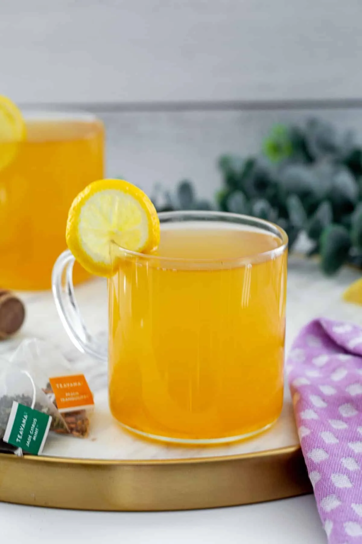 Trà Honey Citrus Mint Tea đã pha chế với lát chanh tươi đặt bên cạnh và túi trà trong nền.