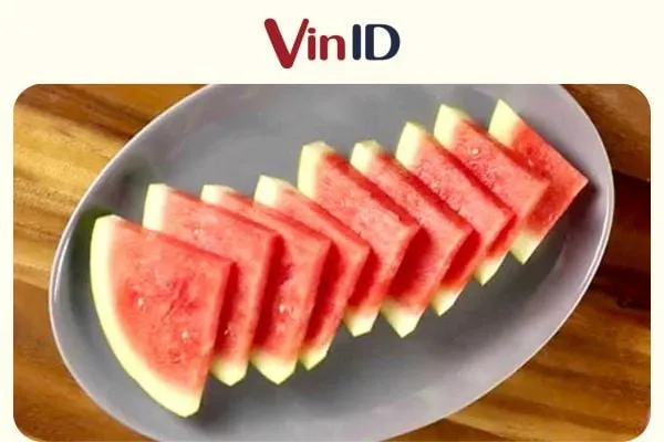 Đĩa dưa hấu được cắt thành miếng tam giác truyền thống, tượng trưng cho sự chuẩn bị kỹ lưỡng trước khi xử lý kỹ thuật vỏ cây cà phê